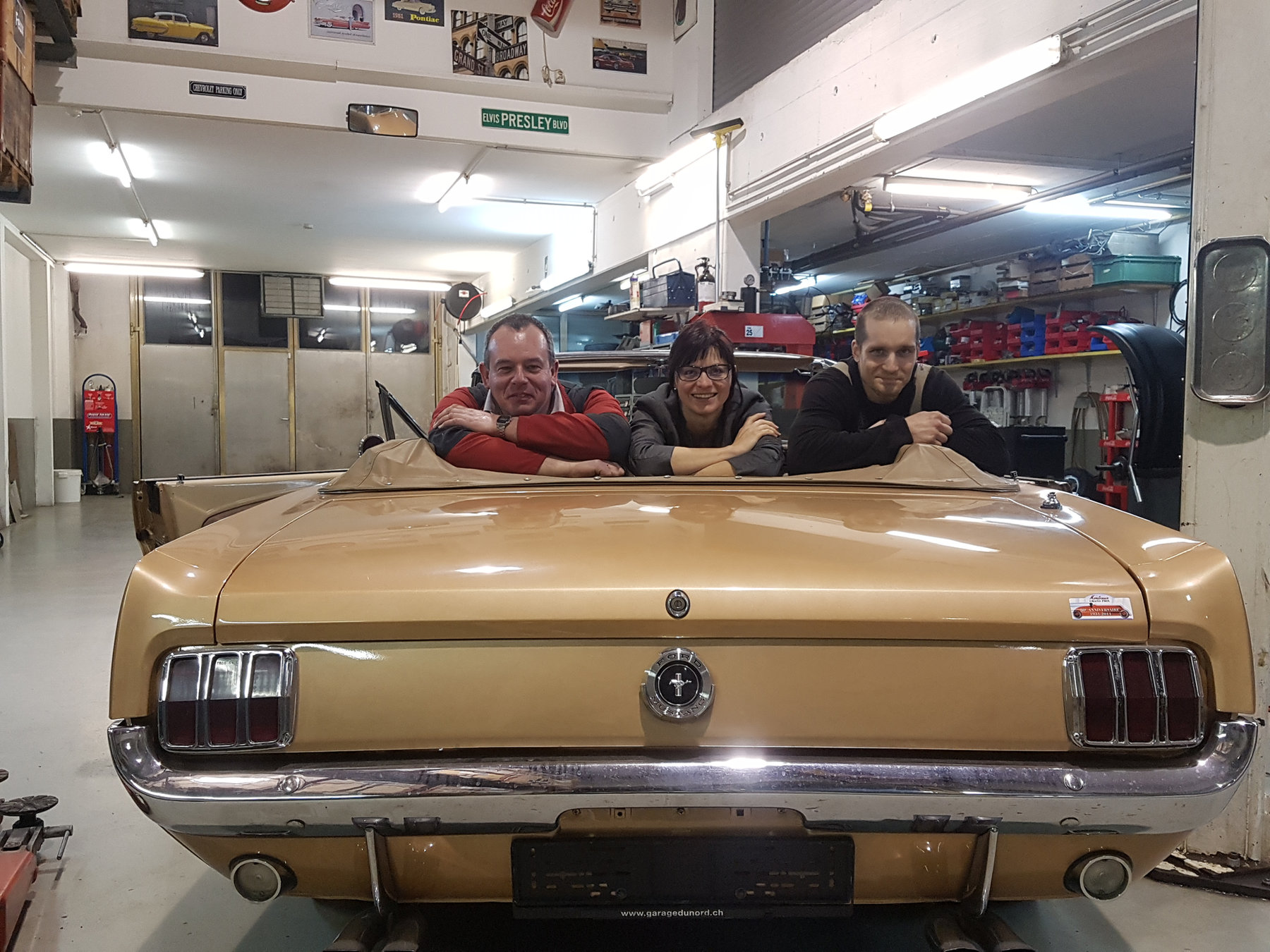 L'équipe du Garage USA dans une Ford Mustang cabriolet, à l'atelier